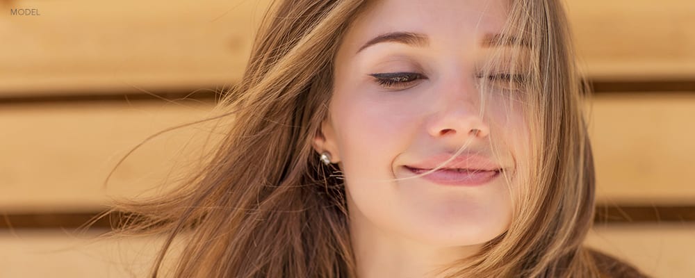 Close Up of Young Woman Softly Smiling with Hair in her Face