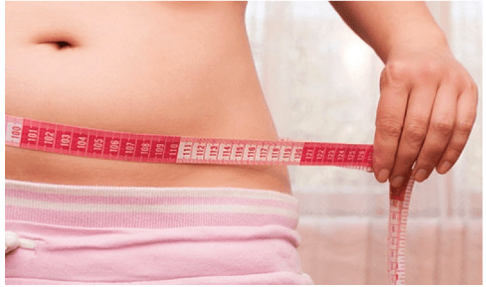 Close Up of Women's Waist as She Measures it with Measuring Tape