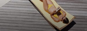 Overhead Shot of Woman In Yellow Bikini Reading a Book Poolside