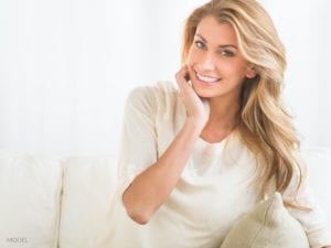 Blond Ocala Woman With Beige Blouse Sitting on Couch Considering A Non-surgical Facelift
